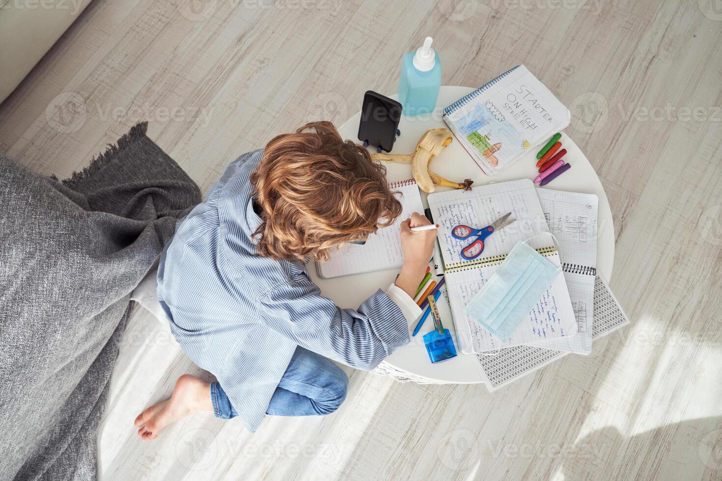 Unrecognizable boy writing in notepad during quarantine photo