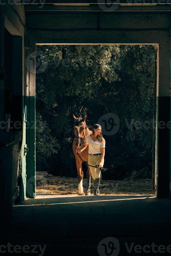 Horsewoman leading horse in barn photo
