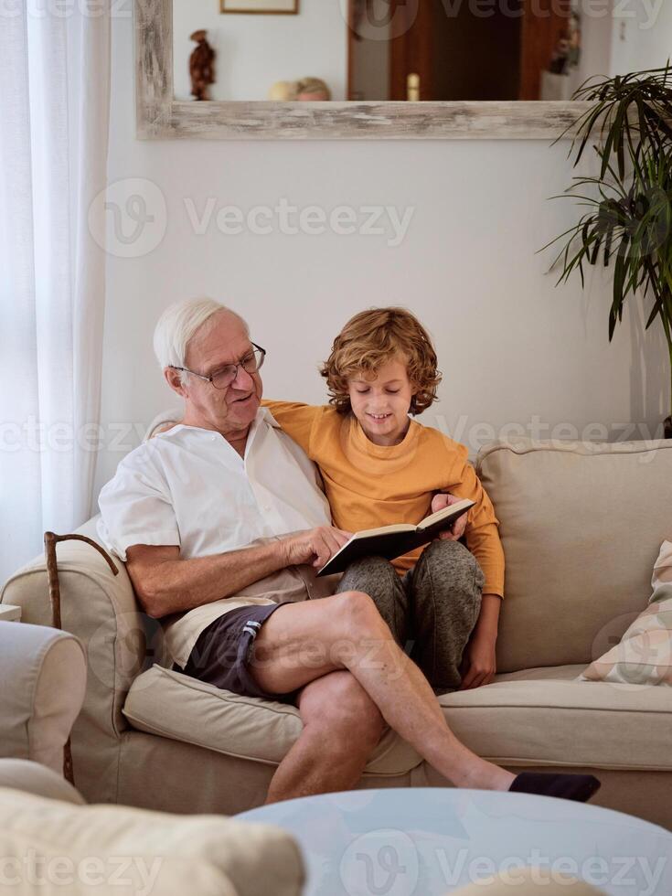 Boy and grandfather reading book on couch during free time photo