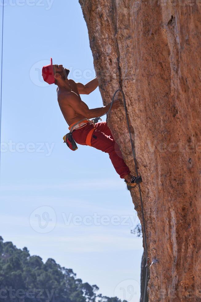 Strong man climbing rocky mountain photo
