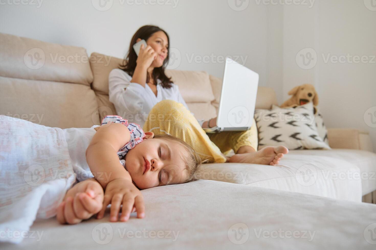 Sleeping daughter resting near mother with laptop and smartphone photo