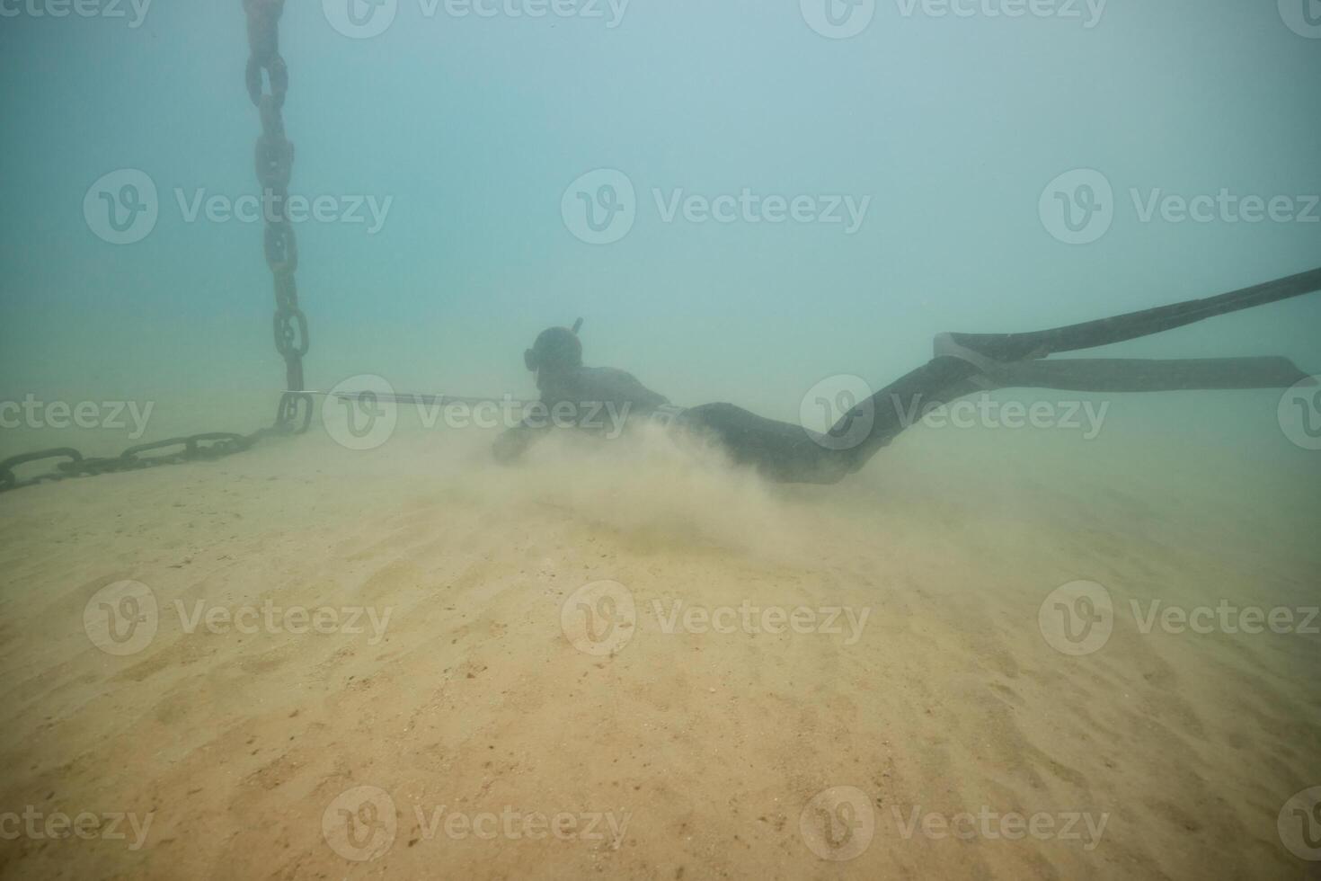 Anonymous diver with harpoon hunting in deep sea photo