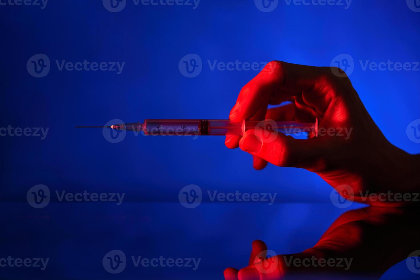 Unrecognizable person with syringe in neon lighting photo