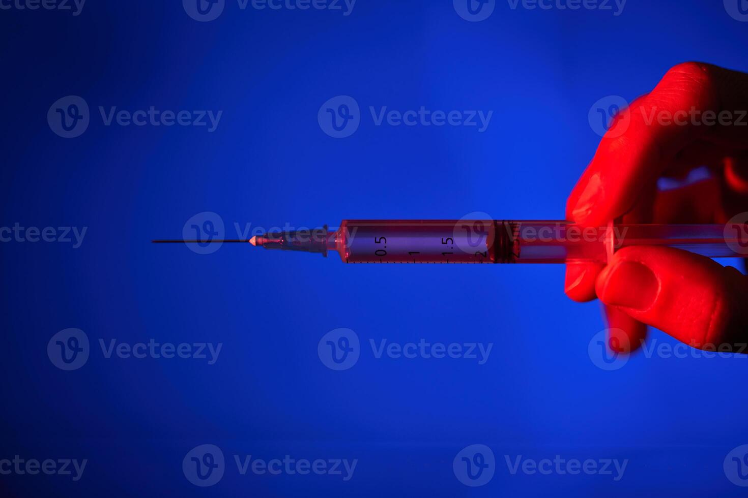 Anonymous person with syringe in neon lighting photo