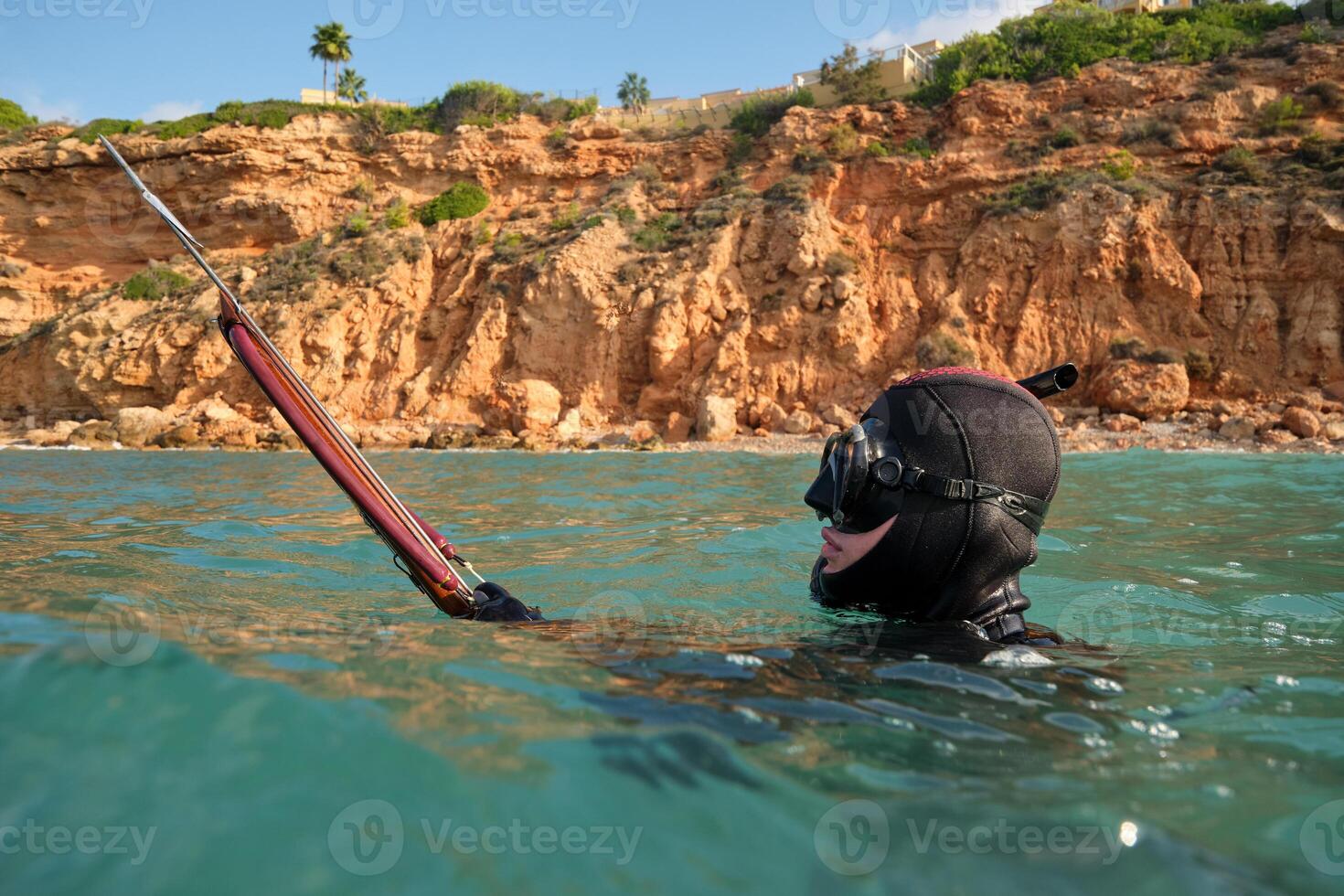Man with speargun hunting in blue sea photo