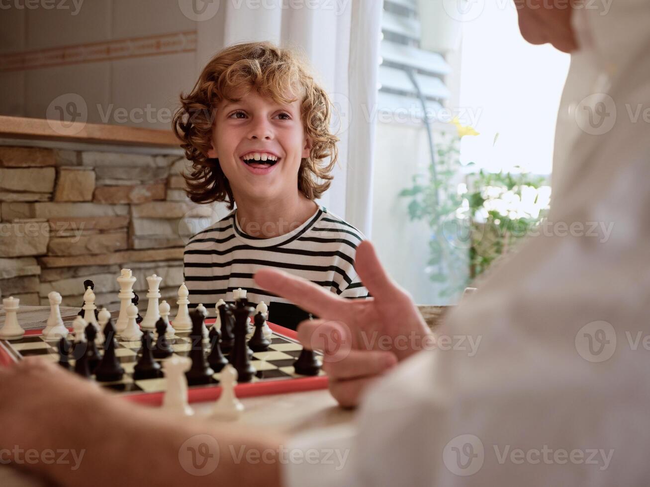 Faceless grandparent playing chess with boy photo