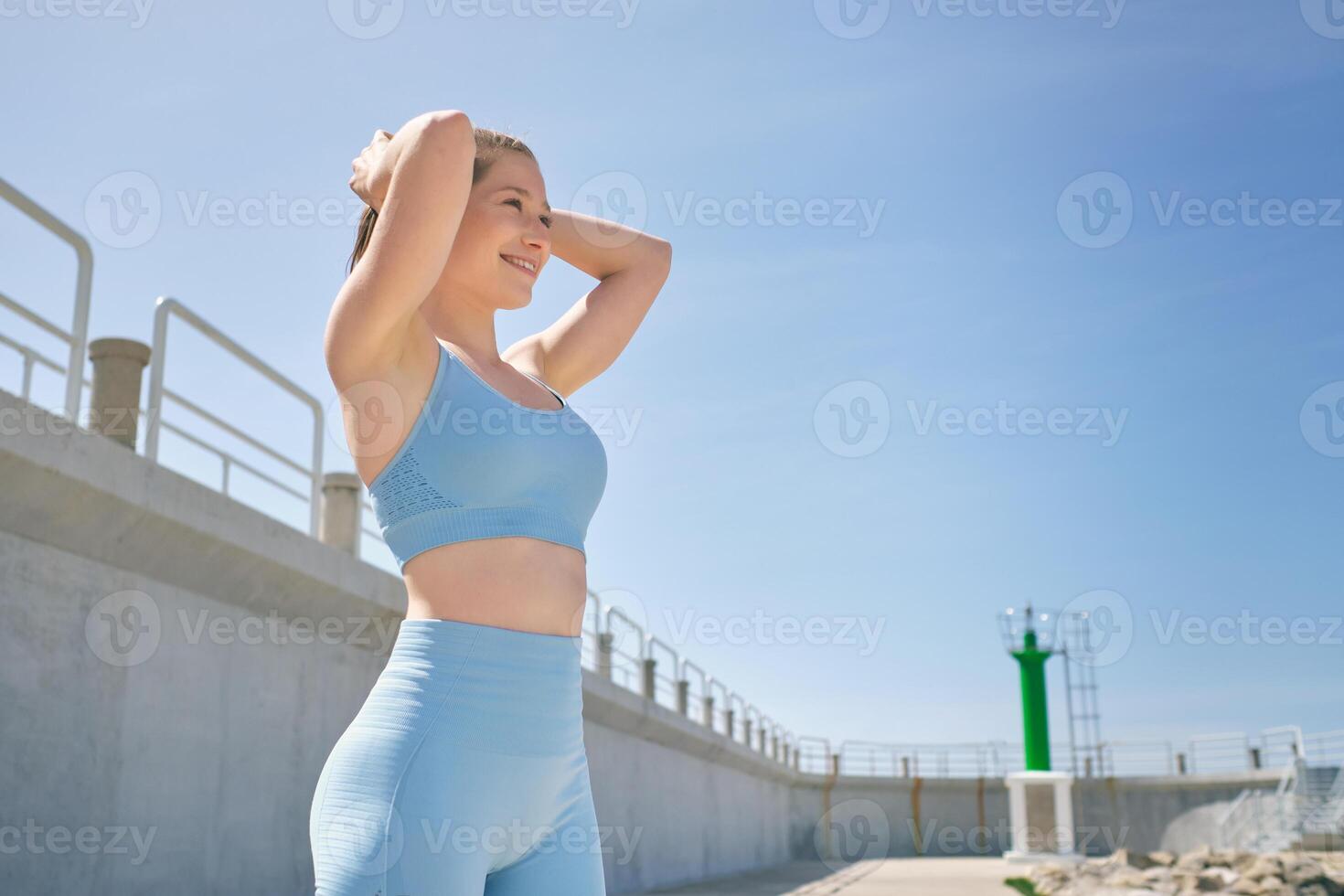 Cheerful sportswoman with curved body under cloudy blue sky photo