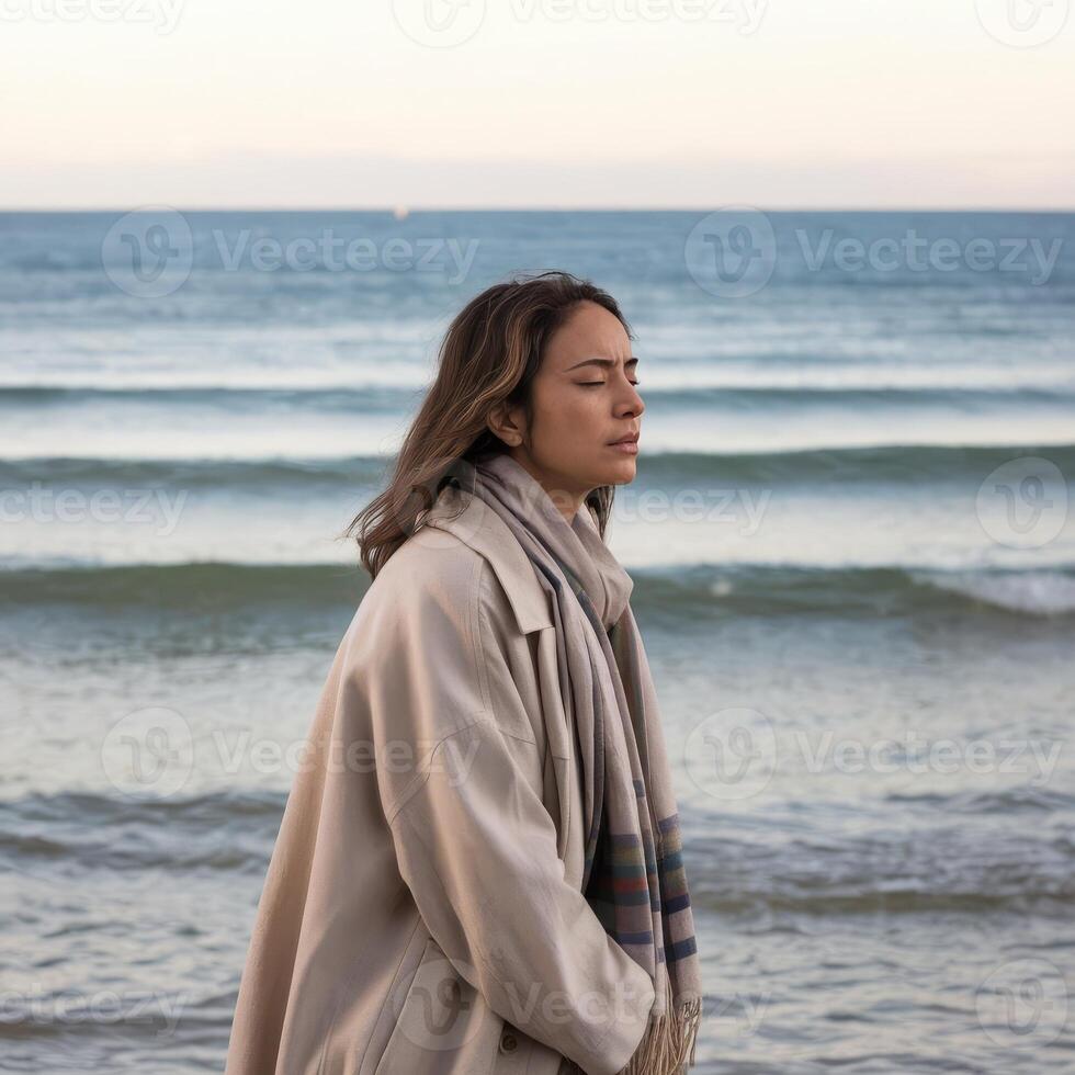 A woman standing on the beach with her eyes closed photo