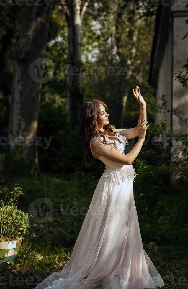 Stunning bride gracefully poses in a spring park, among blossoming trees. exuding elegance, romance and timeless charm. long soft pink wedding dress with a European style corset photo
