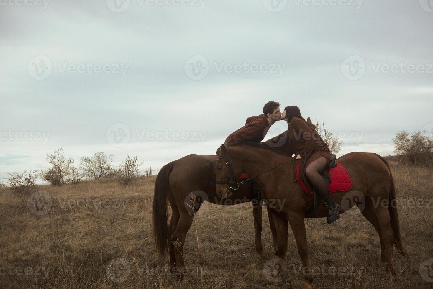 young romantic couple kissing and horse riding. beautiful couple gulet with horses in autumn field during romantic honeymoon. photo