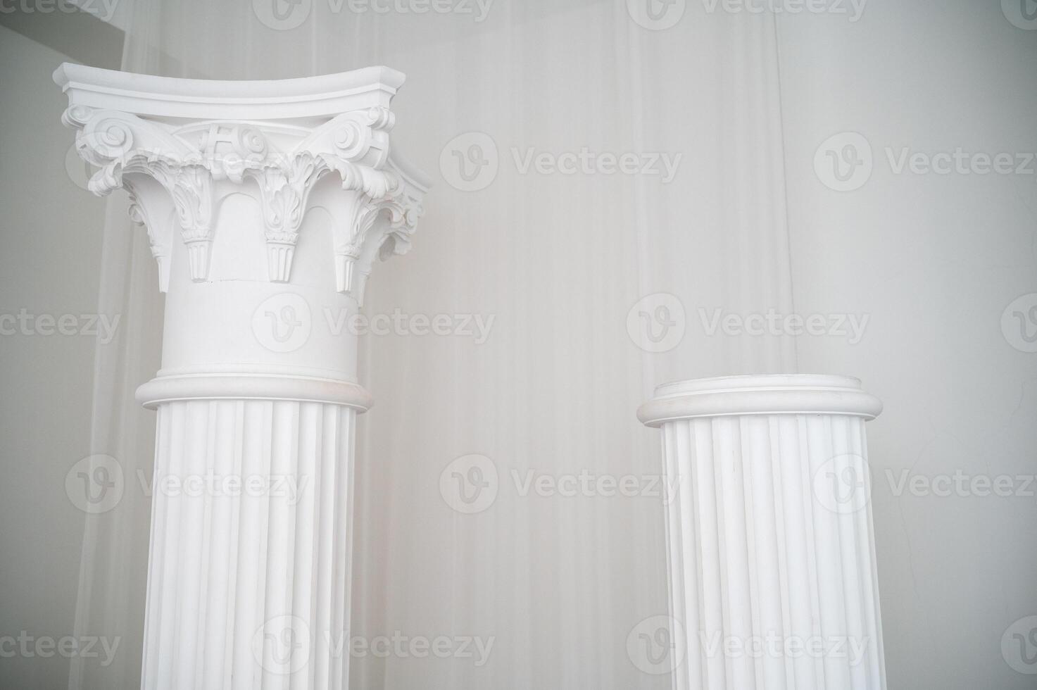 element of antique column in interior. photo zone for photo sessions. two white columns are located in interior. white chiffon fabric is planted.