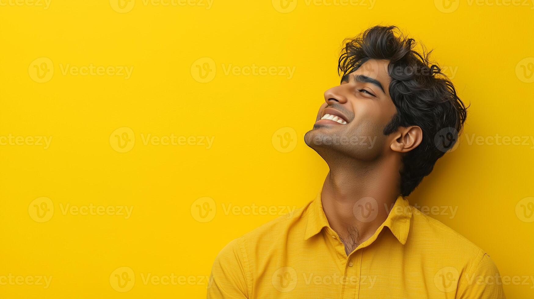 A man with a smile on his face is looking up at the camera. The yellow background adds a warm and cheerful atmosphere to the image photo