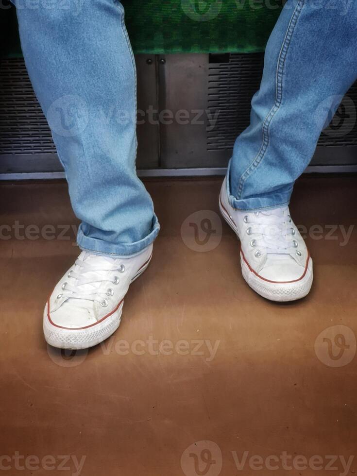 A person sitting on a subway train with their feet on the floor photo