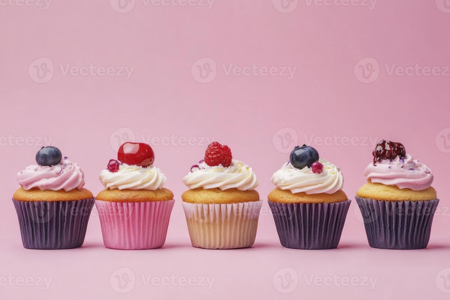 Row of Cupcakes with Frosting and Berries Against a Pink Background photo