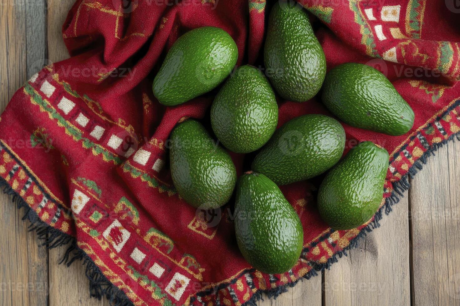 Green Avocados Displayed on Decorative Red Cloth Over Rustic Wood Surface photo