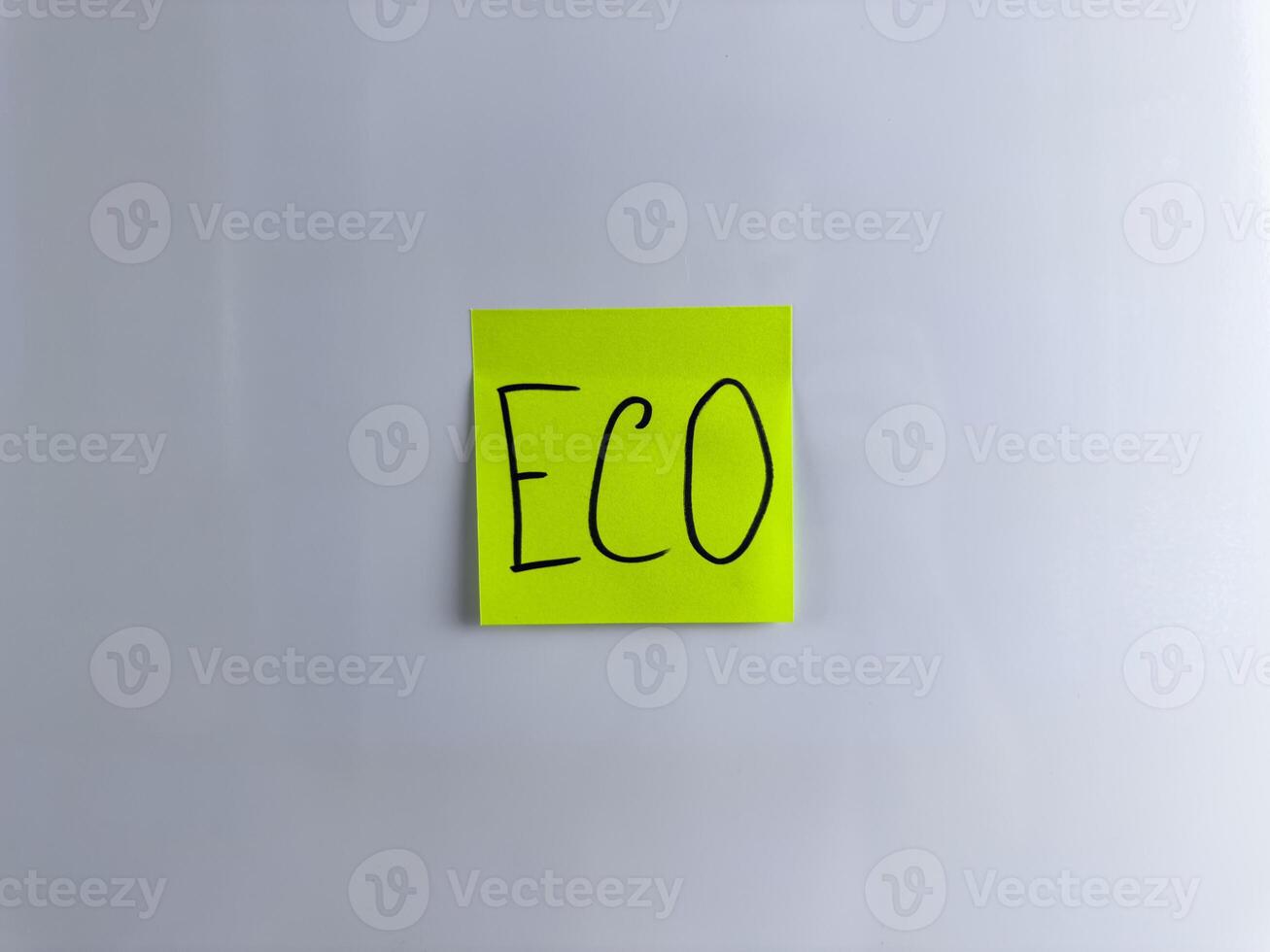 Green sticky note is glued to white background with handwritten word Eco photo
