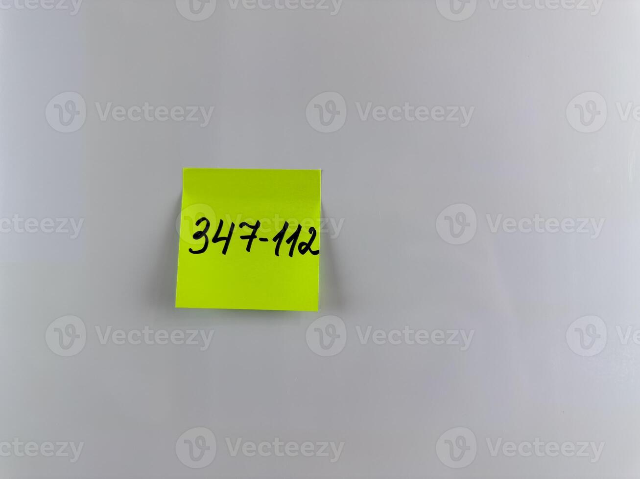 Phone number is written with marker on bright sticky note photo