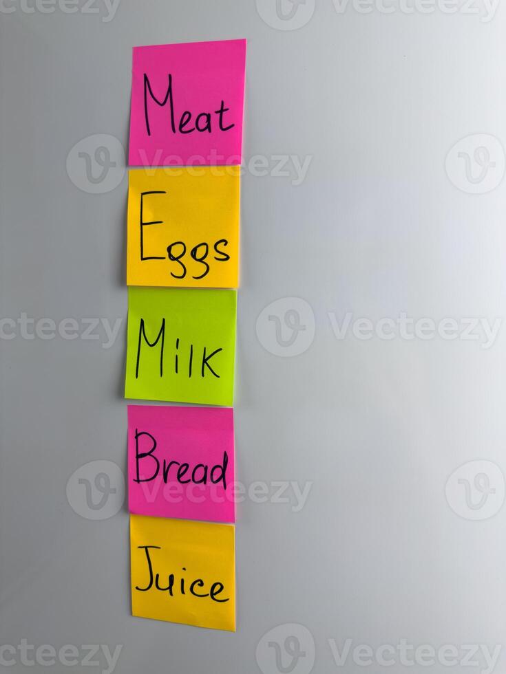 Grocery list written on colored sticky notes. Reminder of what food to buy for home photo