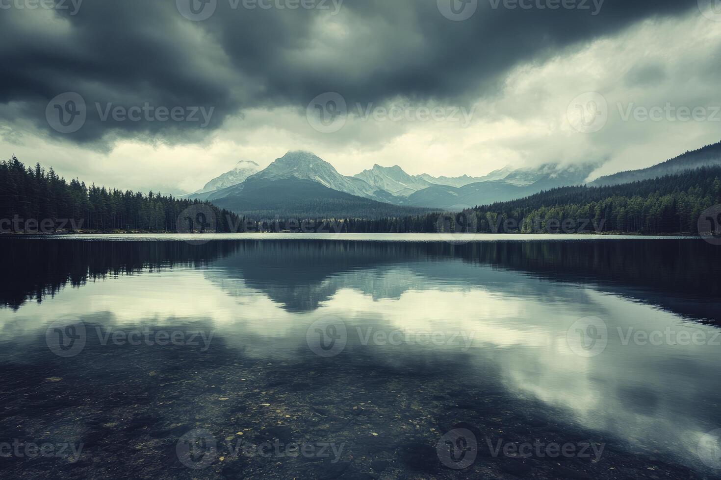 Reflecting Lake Landscape with Forest and Mountains Under Stormy Sky photo