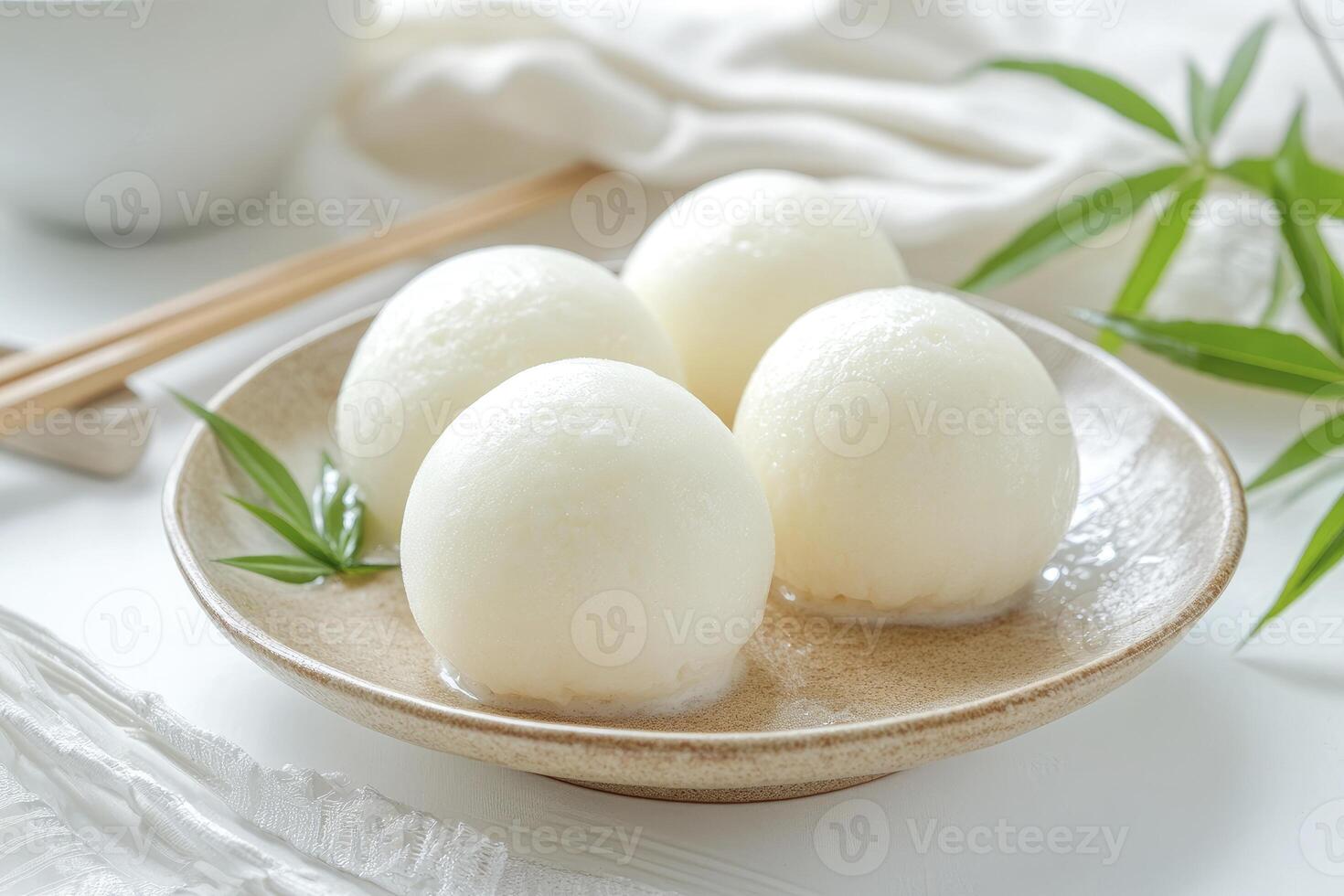 Enjoying Mochi Dumplings on Plate with Chopsticks and Green Leaf photo