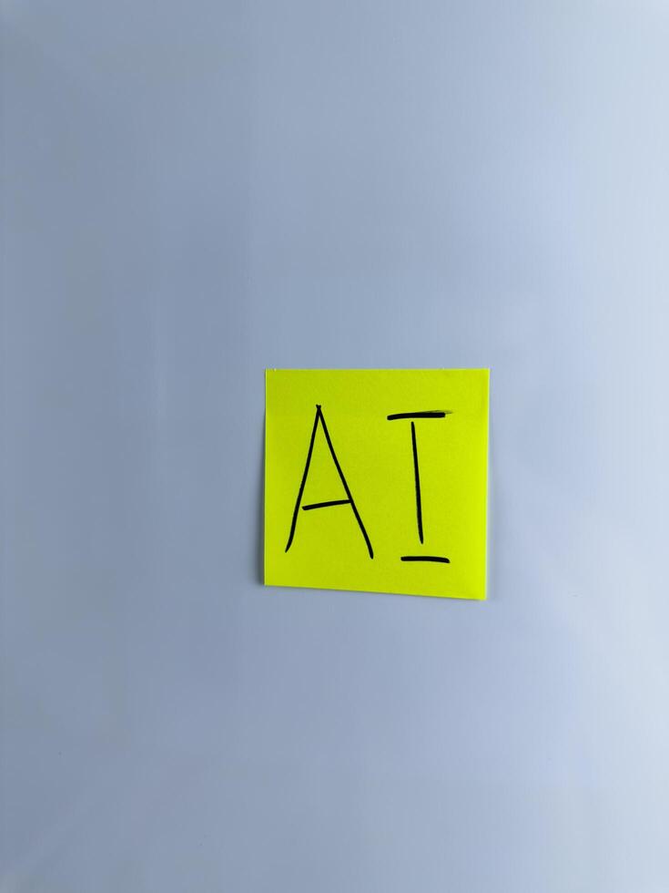 The abbreviation AI is written on sticky note on white background photo