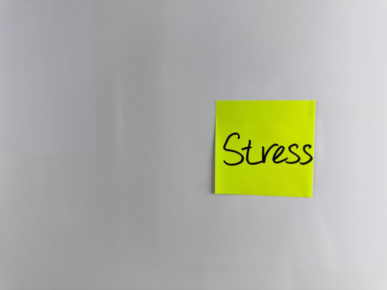 The word Stress is written on sticky note with marker photo