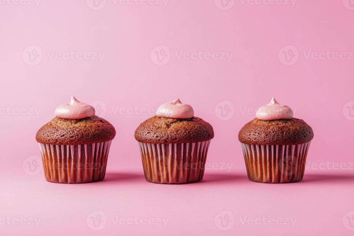 Three Cupcakes with Pink Frosting on a Pink Background Dessert Treat photo