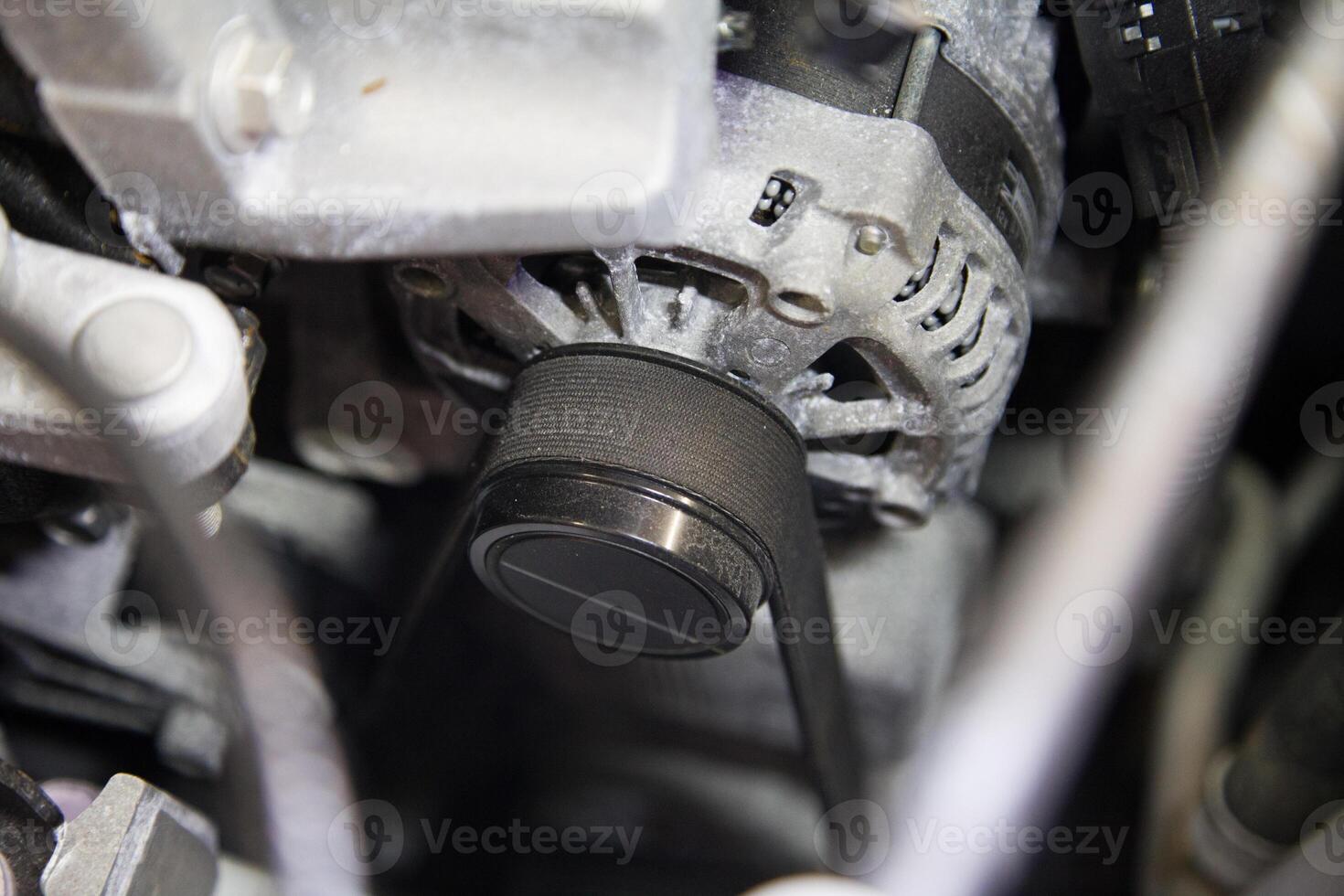 Close up of the engine belt tensioned on the retractor pulley under the car hood photo