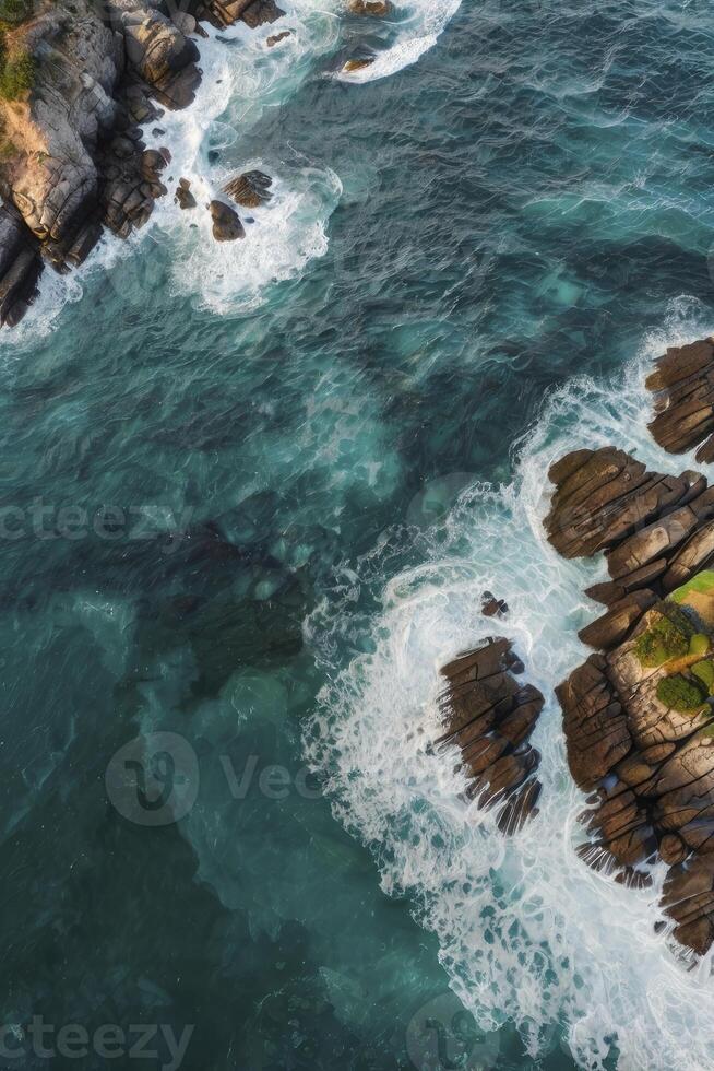 Aerial View of Waves Crashing on Rocky Coastline Azure Ocean Water photo