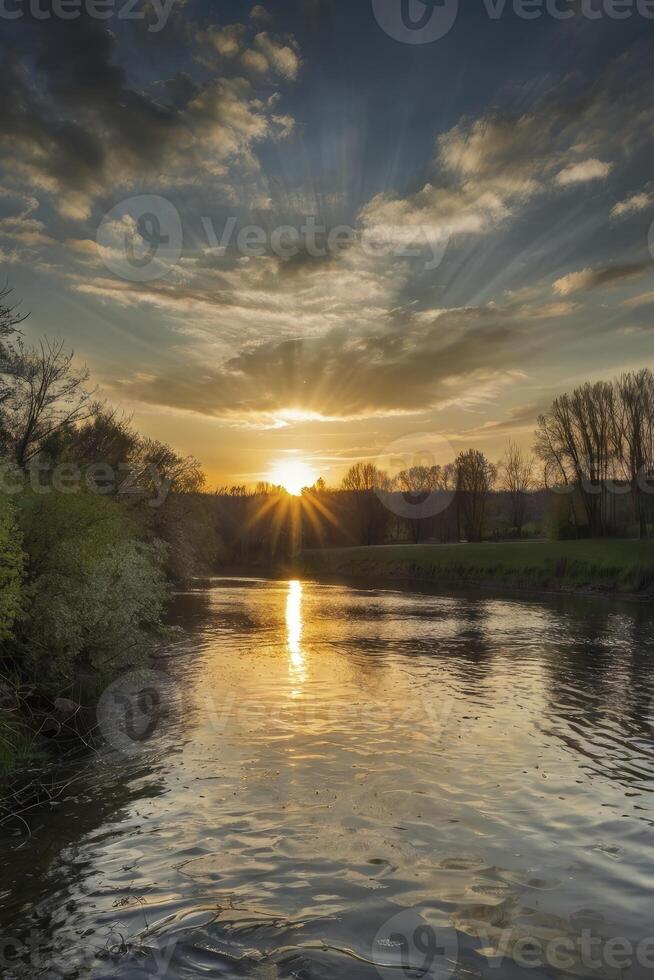 River Flowing at Sunset with Sun Rays Shining Through the Clouds photo