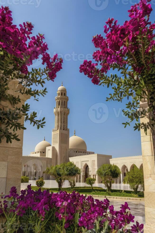 Mosque with Tower Framed by Pink Flowers and Green Trees on Sunny Day photo