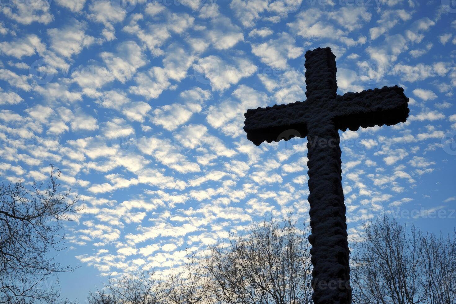 Stone Cross Silhouette Against a Stunning Cloudscape with Trees Below photo
