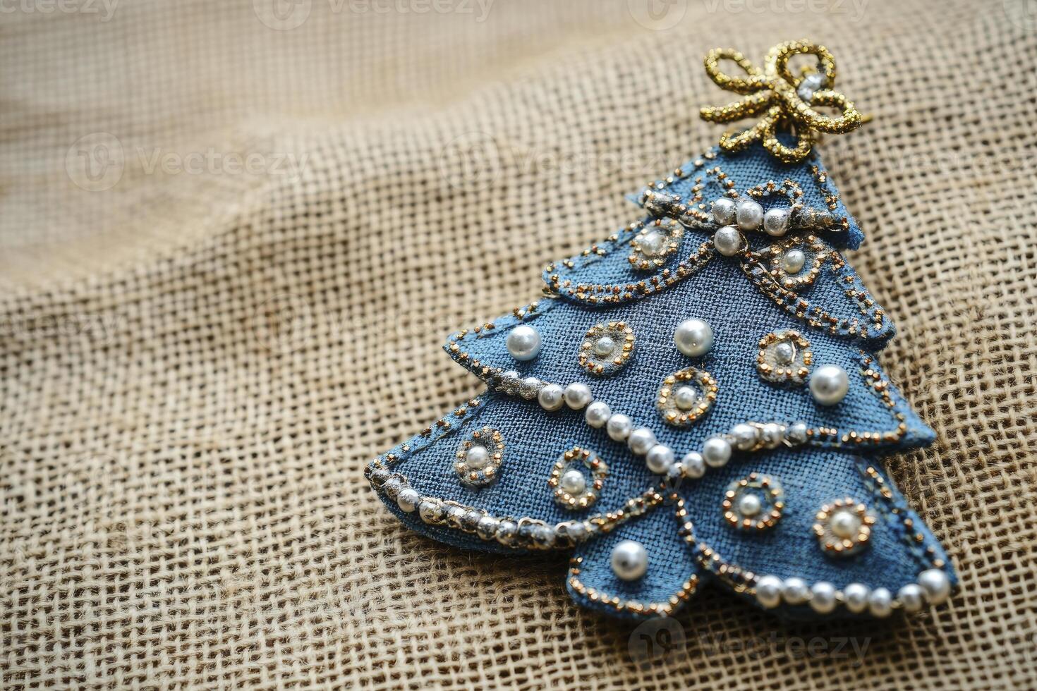 Denim Christmas Tree Ornament with Pearls on Burlap Background Close Up photo