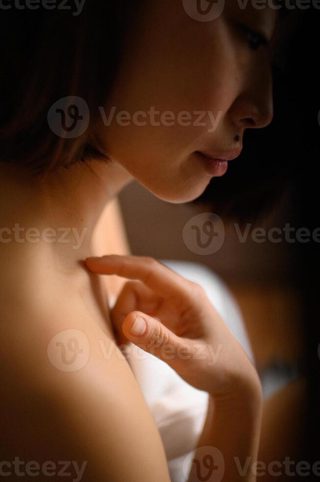 With a serene expression, she gently touches her skin, the warmth of her fingertips blending with the glow on her face. photo