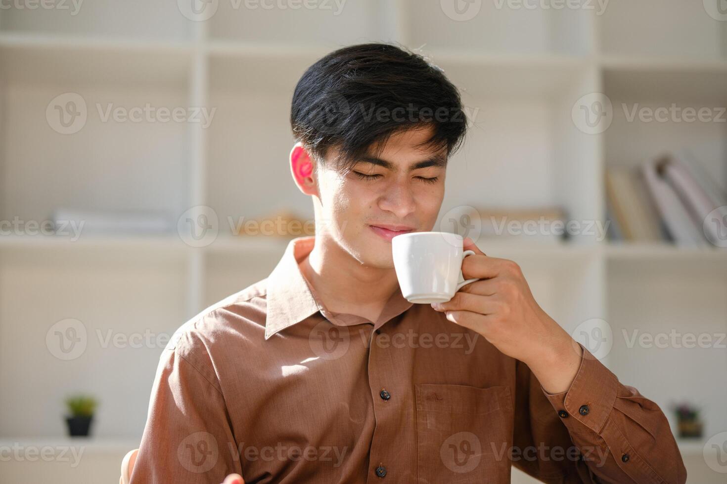 Young man reacting to the strong taste of coffee while taking a break at work photo