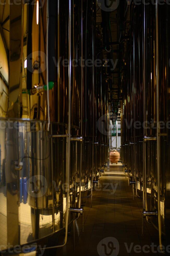 Large stainless steel tanks stand in a winery, ready for the wine fermentation process. photo