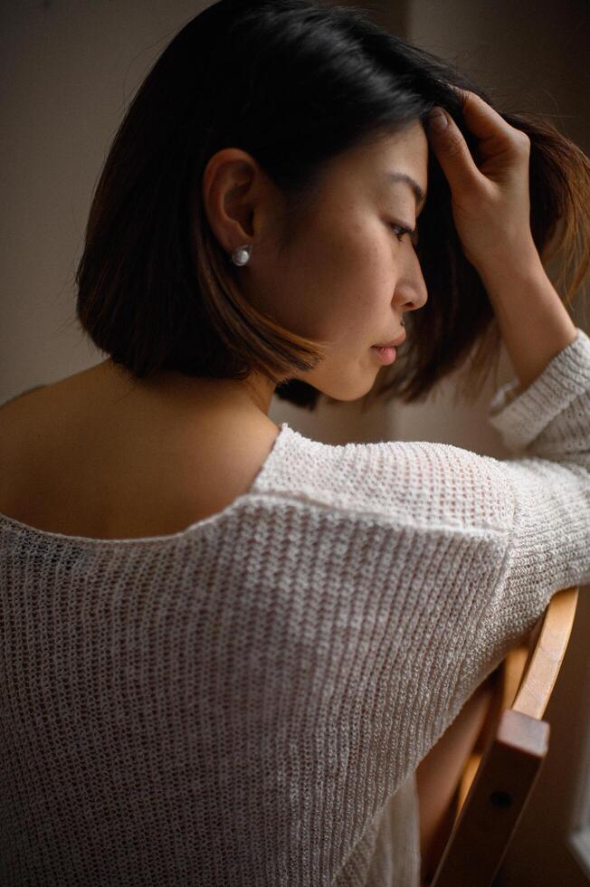 A portrait of an Asian woman in a white knitted sweater with a pearl earring. photo
