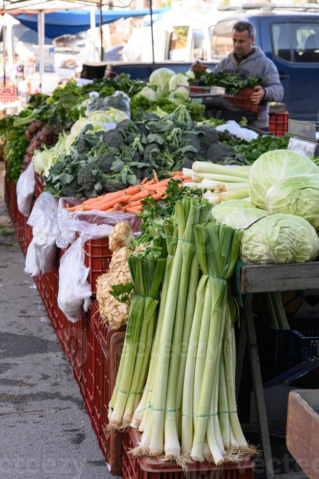 The scent of herbs and earth fills the air as a vendor weighs a gigantic leek for a smiling customer at the organic market. photo