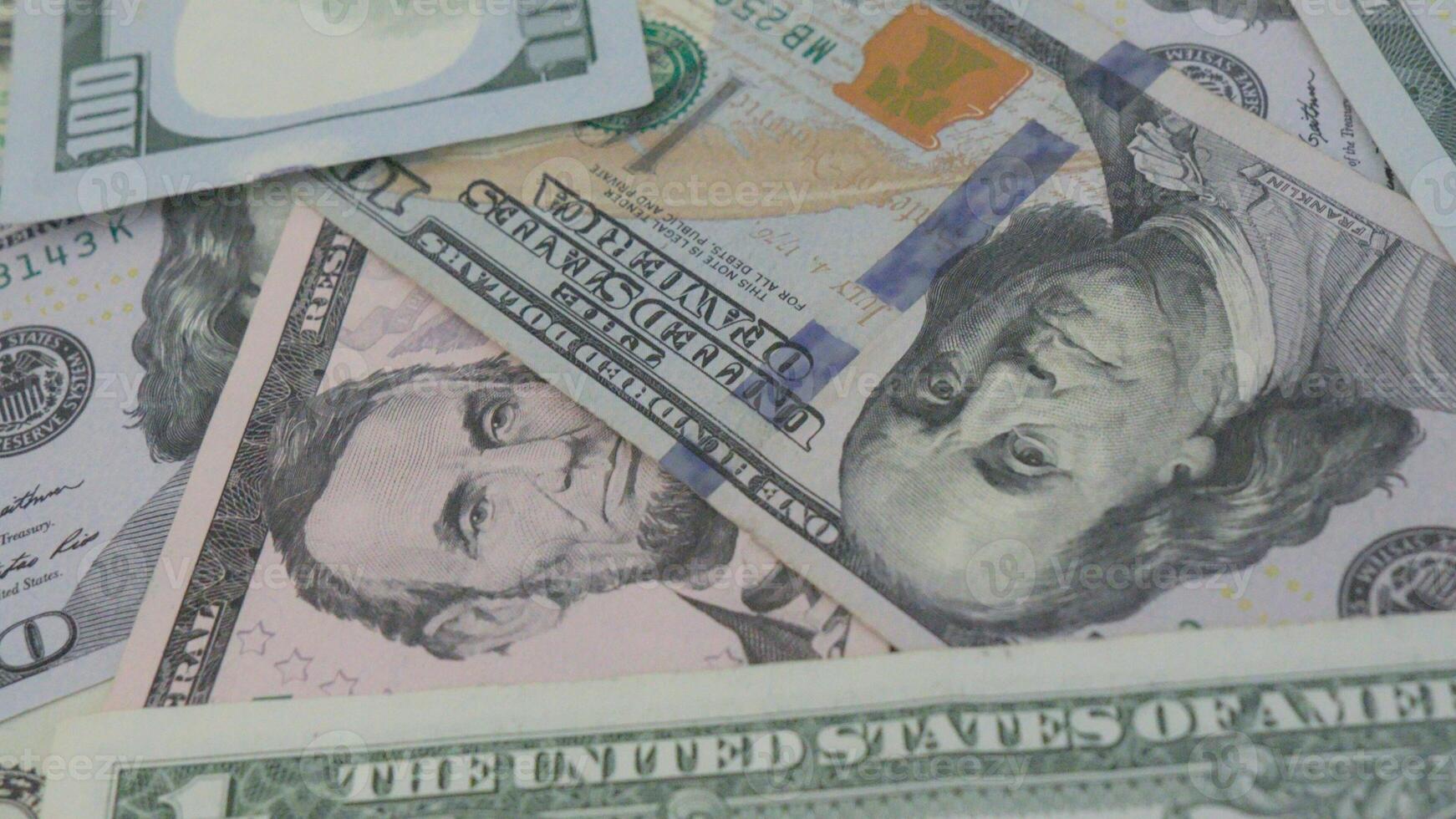 A stack of dollar bills of different denominations, including 1, 5, and 100. photo