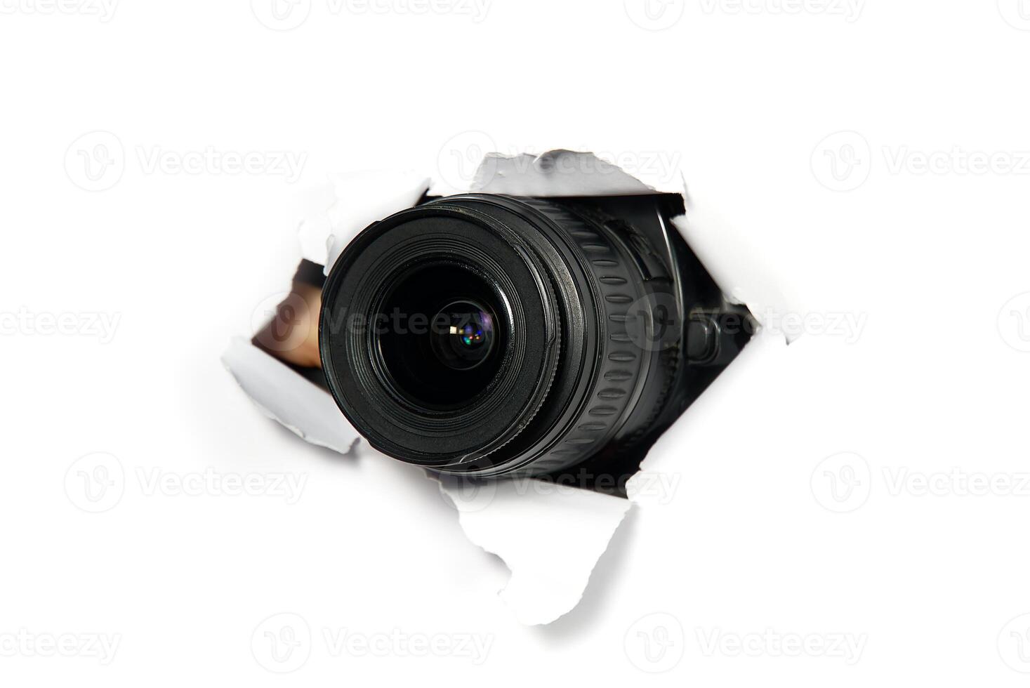 The image features a black camera lens that peeks through a torn white paper background, showcasing a vibrant contrast and sharp focus, perfect for stock photo usage.