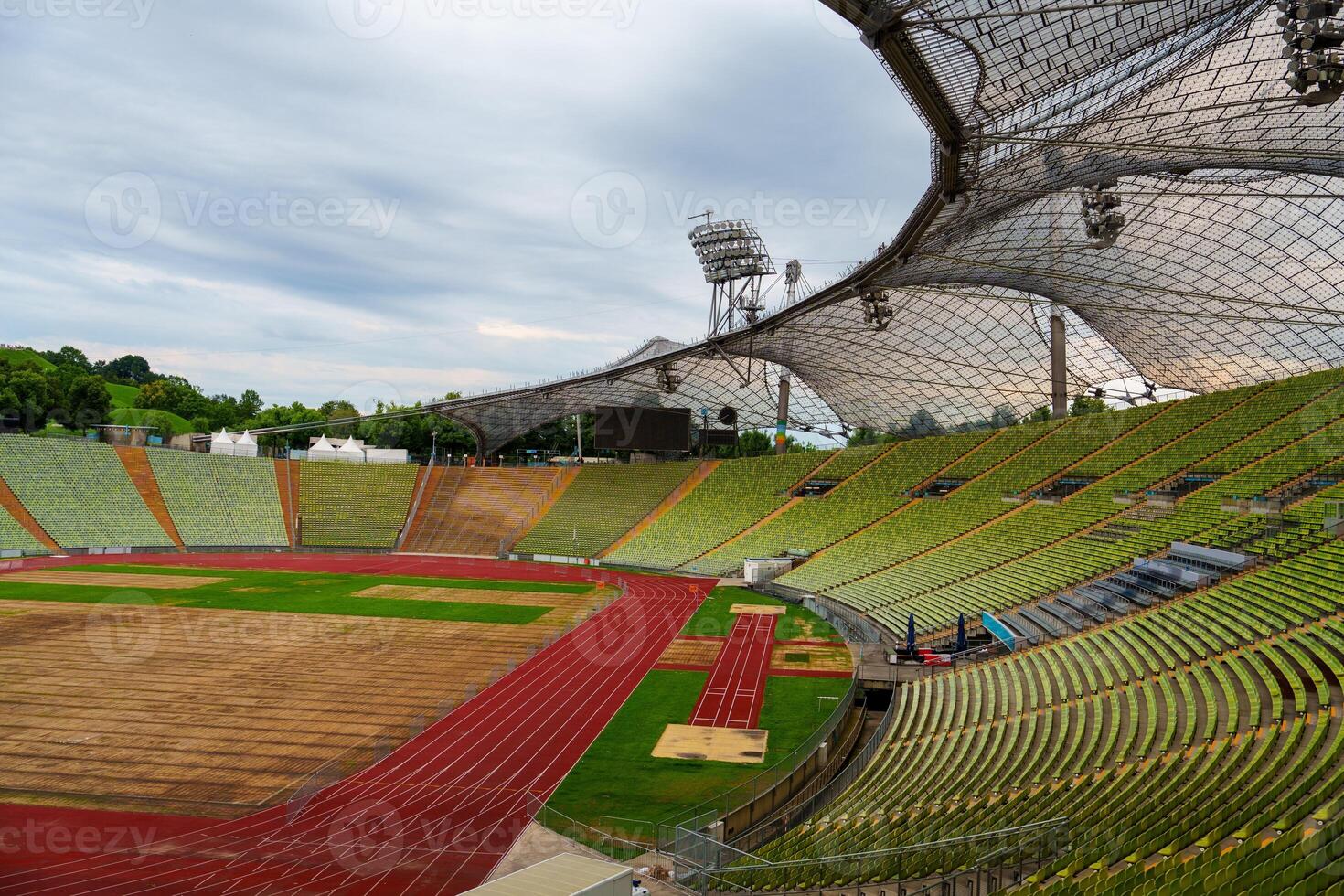 A modern stadium designed for athletics, featuring a professional running track and seating for thousands. Surrounded by trees and a river, it provides a beautiful backdrop for events. photo
