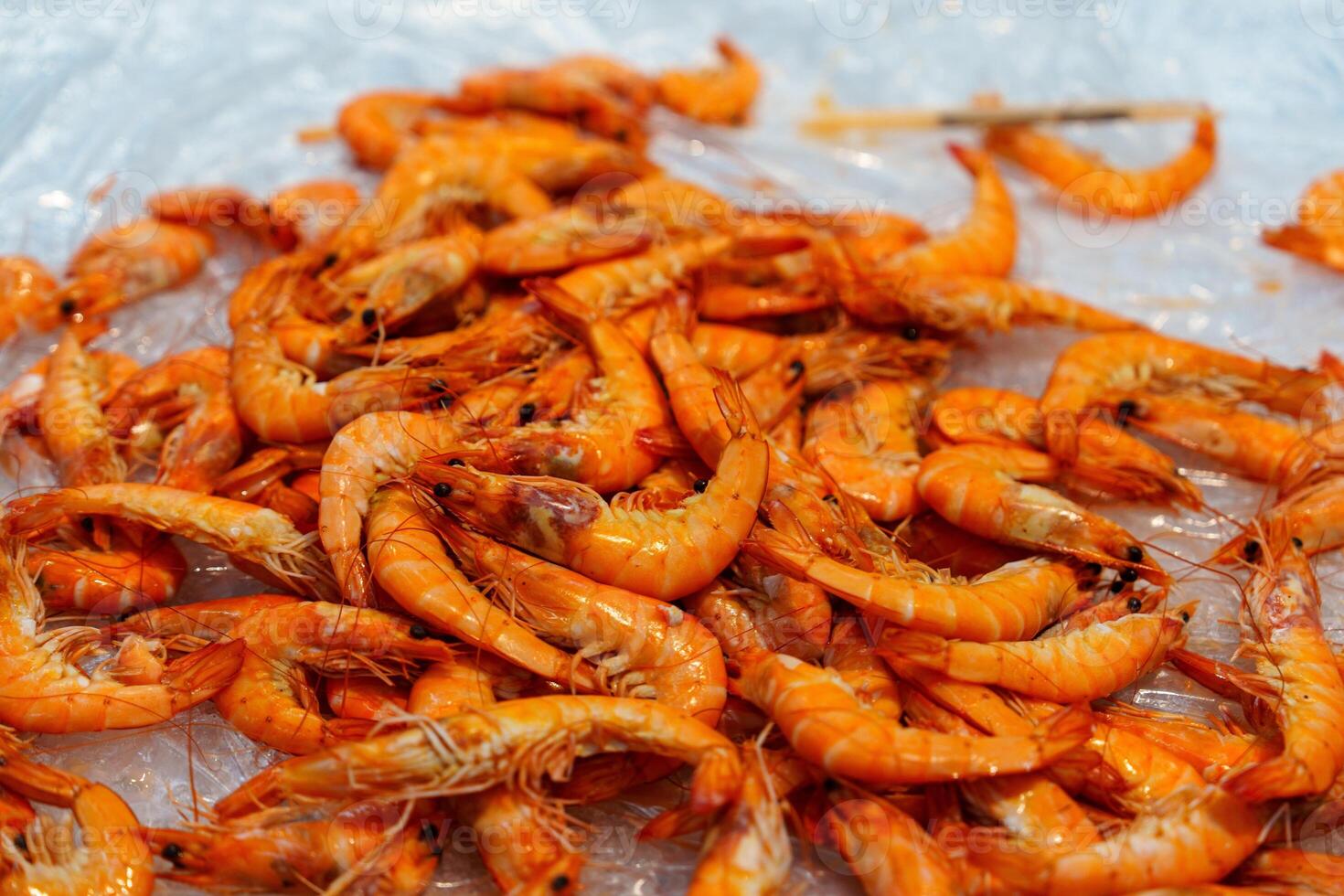 A stunning pile of freshly cooked tiger prawns sitting elegantly on a bed of ice, perfectly prepared and ready to be served to seafood lovers, highlighting their vibrant color and freshness. photo