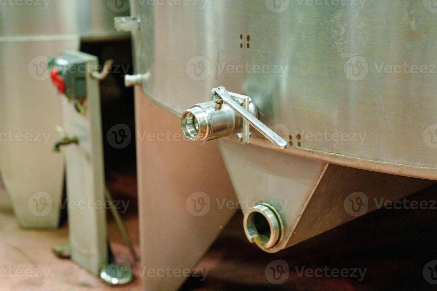 The image showcases a close-up view of a stainless steel tank with a valve, commonly used in food and beverage processing, highlighting its industrial design and functionality. photo