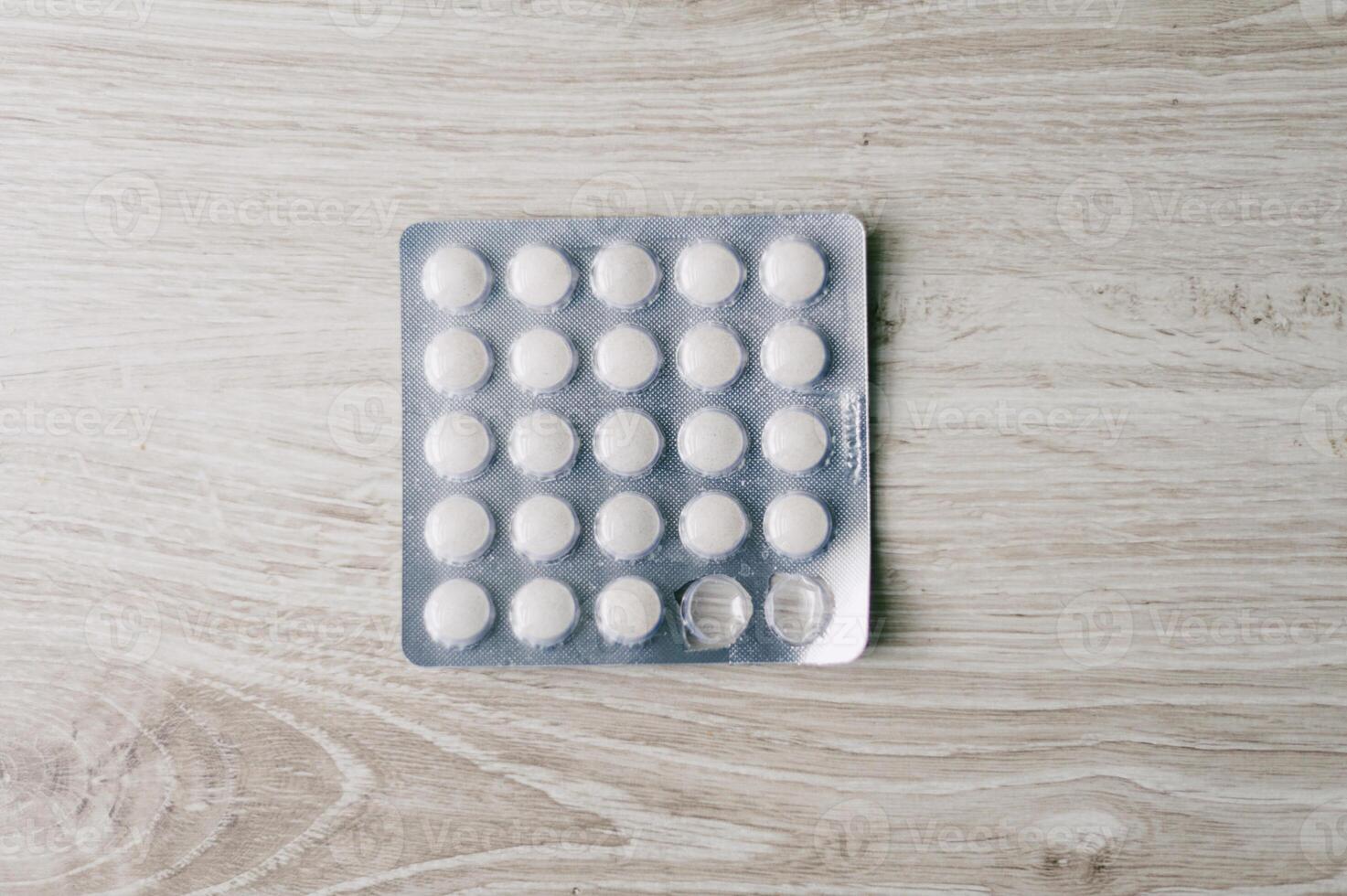 A box of pills is on a wooden table photo