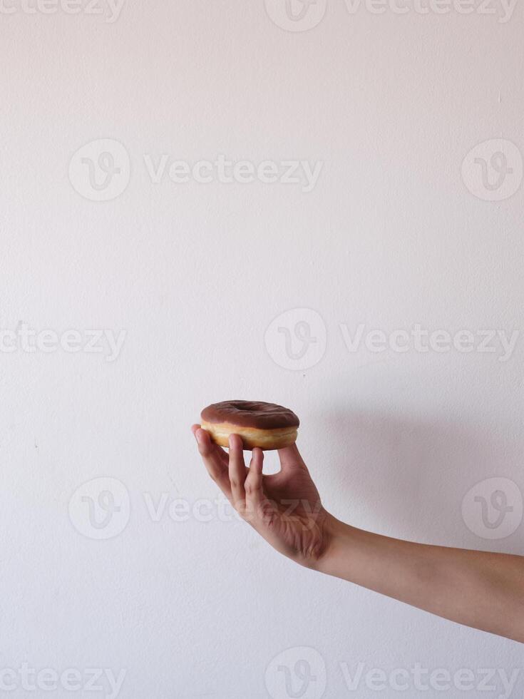 A hand holding a chocolate glazed doughnut photo