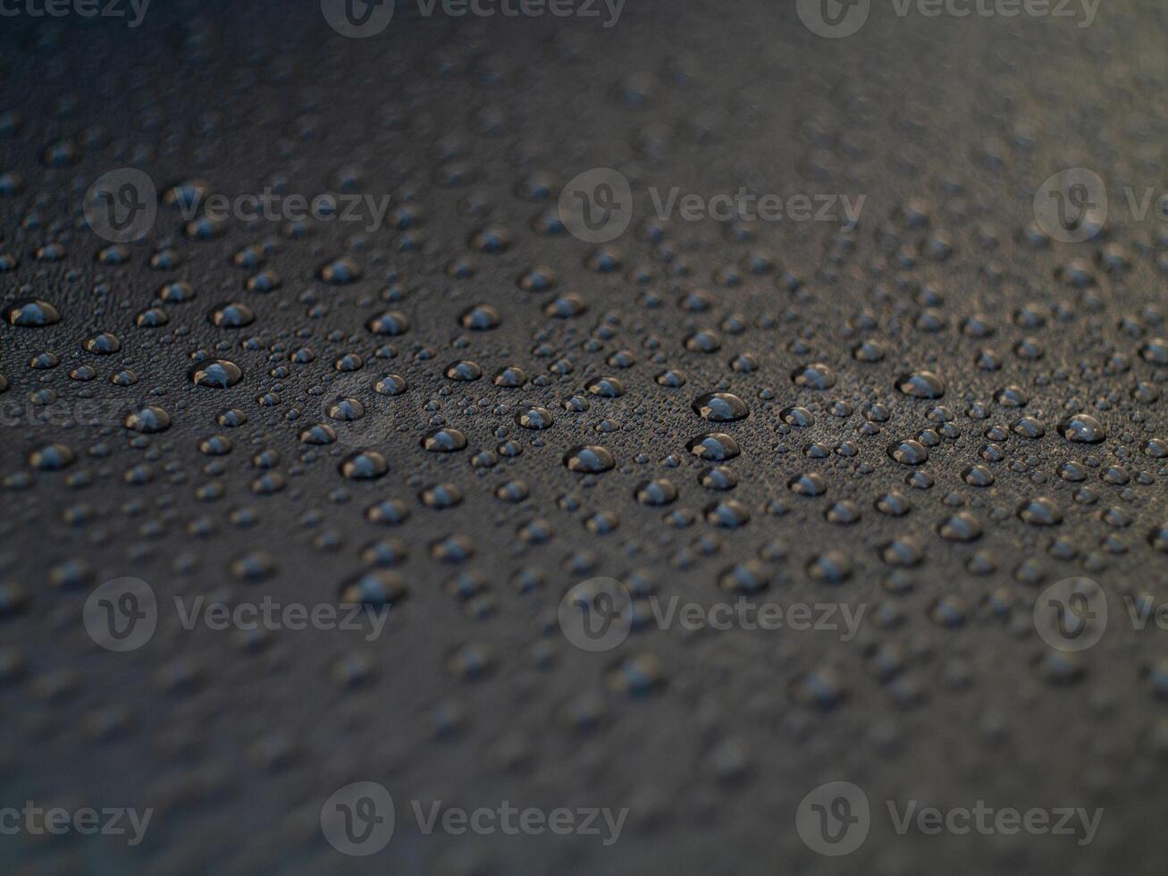 A black surface with many small drops of water photo