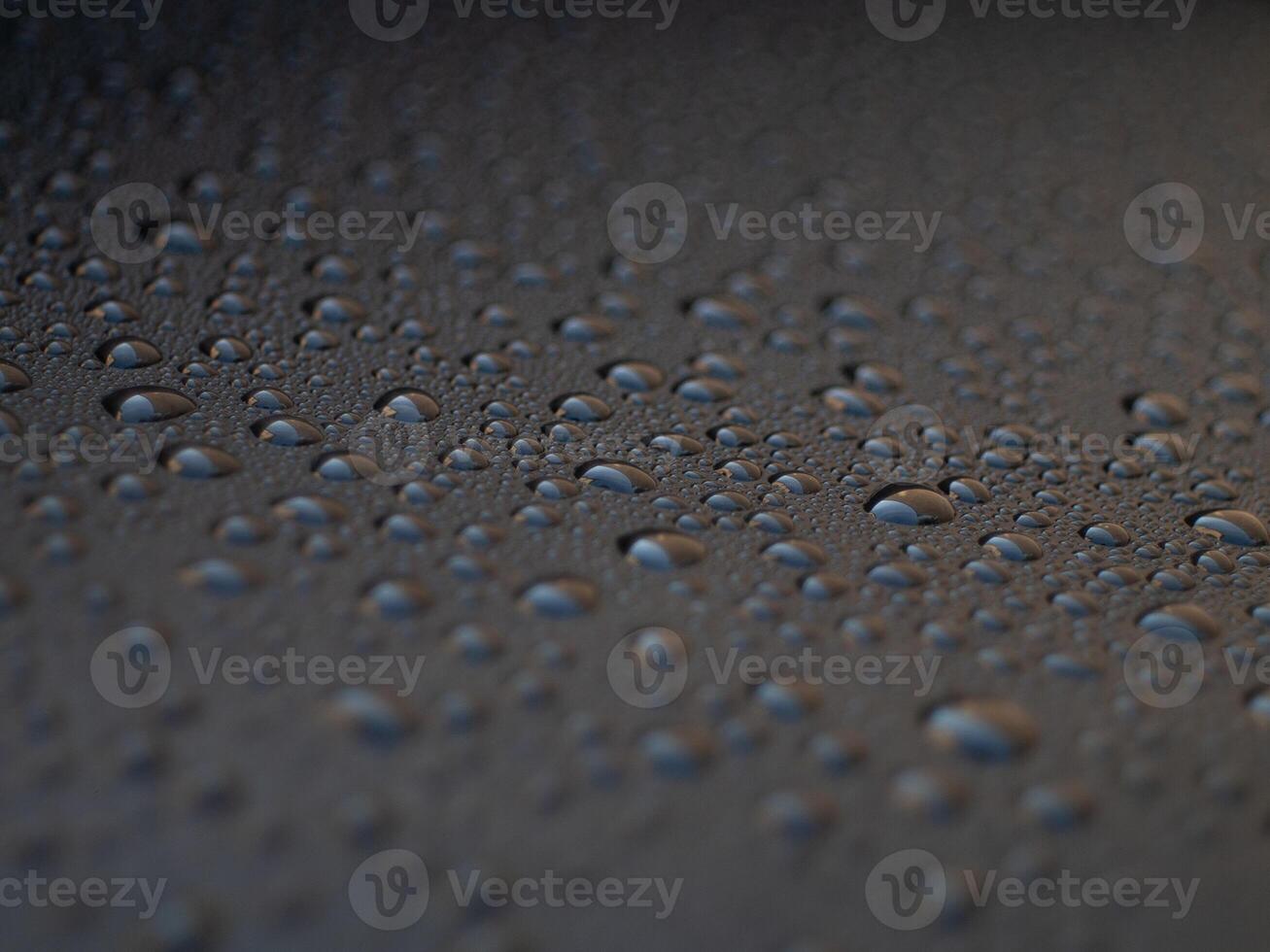 A black surface with many small drops of water on it photo