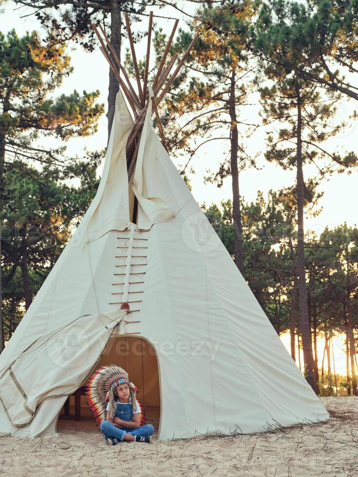 Boy sitting near traditional tipi photo