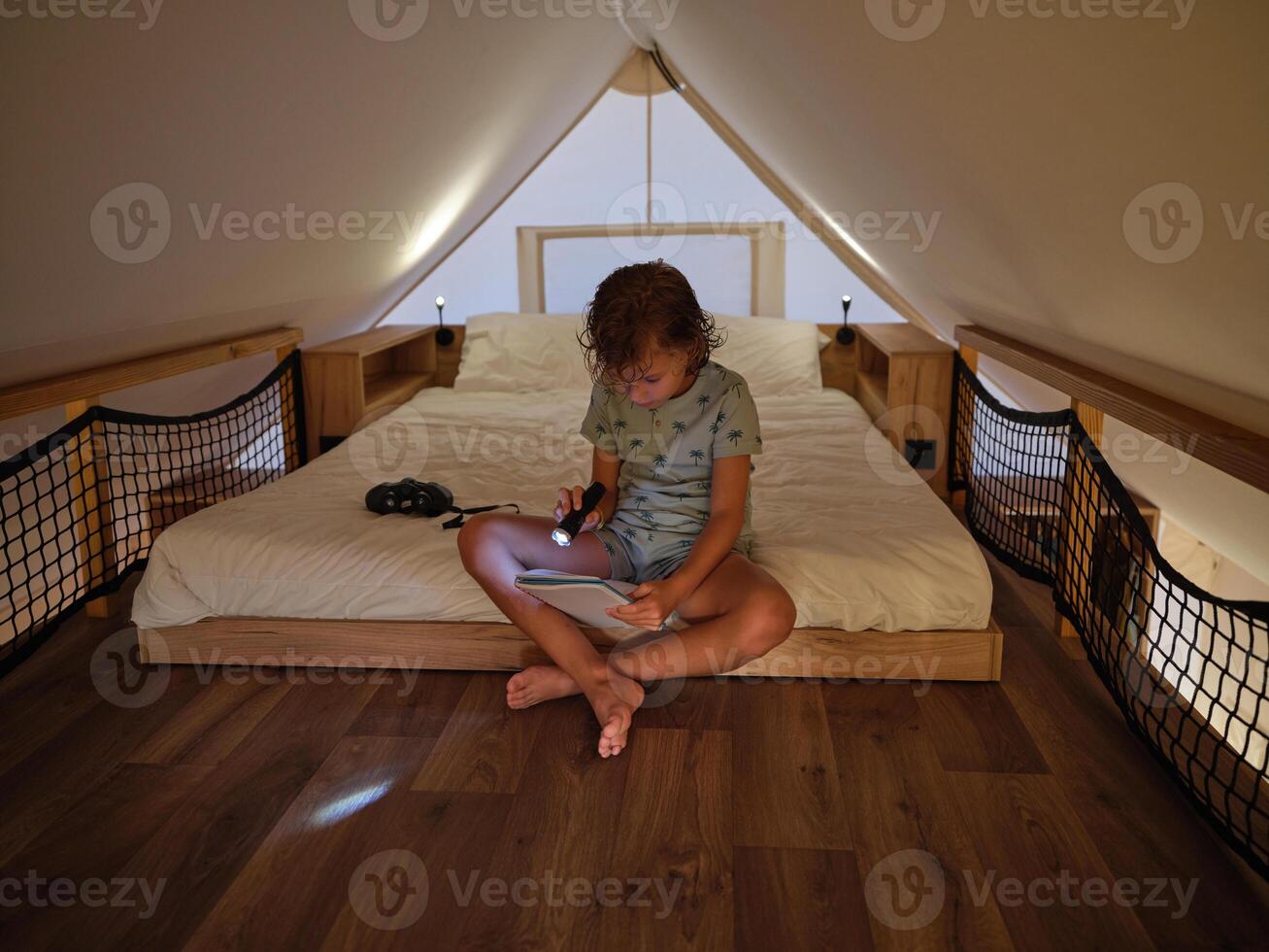 Boy reading notebook with flashlight photo