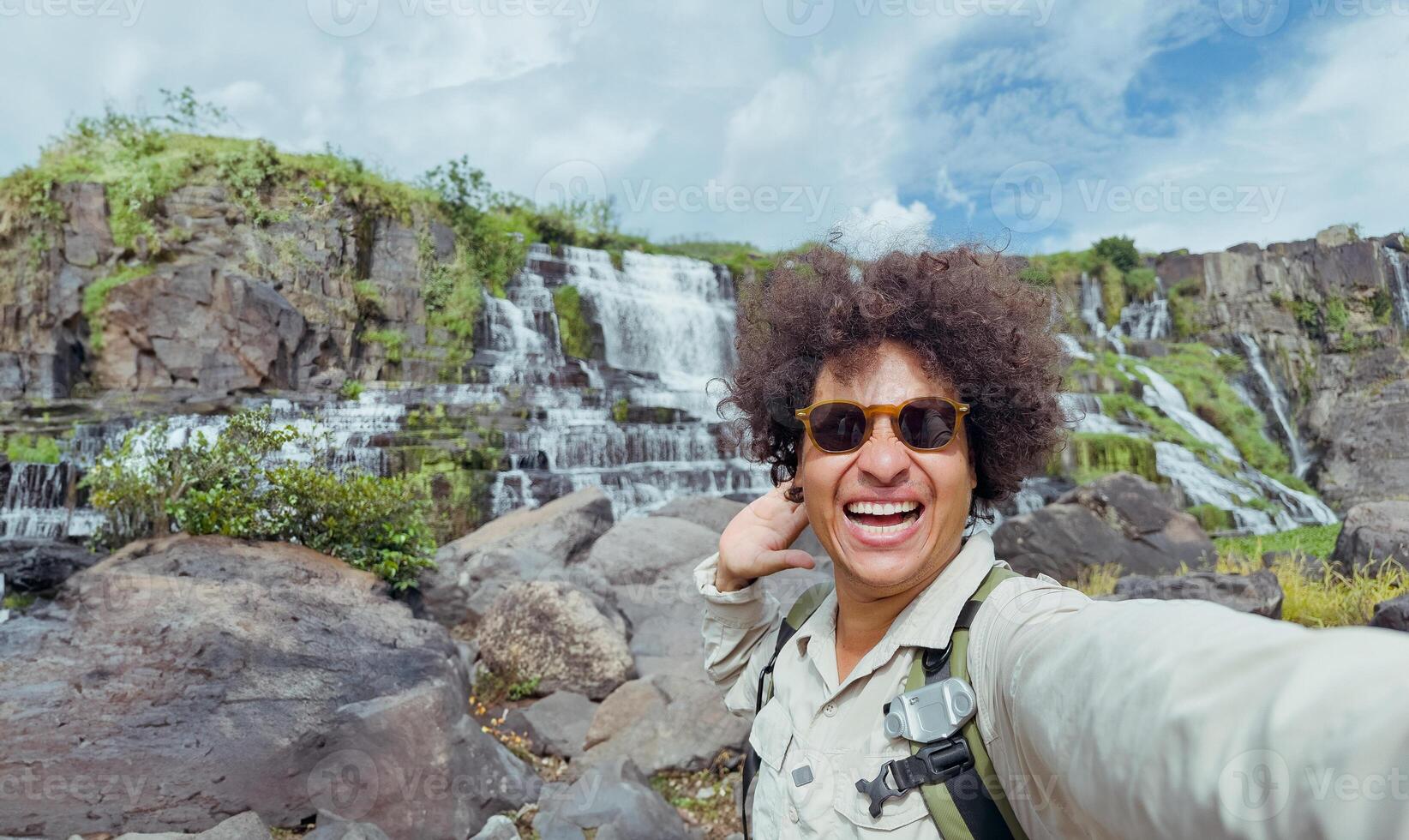 exultant traveler takes selfie with waterfall in the background photo